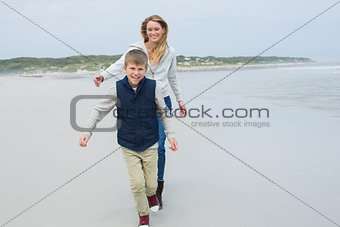 Smiling woman and boy running at beach