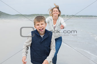 Woman and cheerful boy running at beach