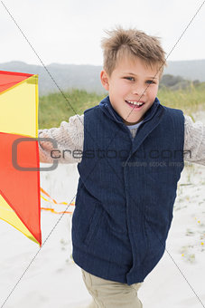 Portrait of cheerful boy with kite at beach