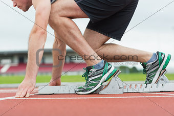 Side view of a man ready to race on running trac