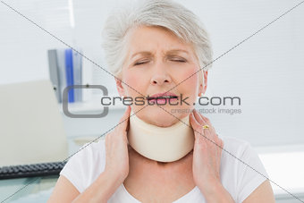 Senior woman wearing cervical collar in medical office