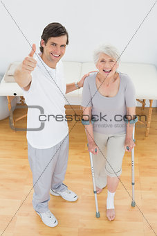 Therapist gesturing thumbs up with senior disabled patient
