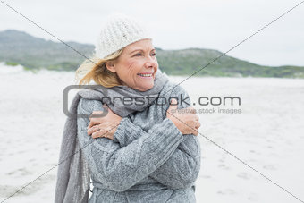 Cheerful senior woman shivering at beach