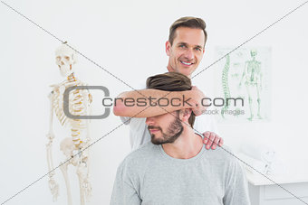 Portrait of a male chiropractor doing neck adjustment
