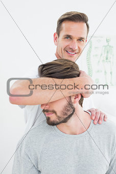 Portrait of a male chiropractor doing neck adjustment