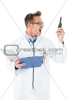 Annoyed doctor with clipboard shouting into a wireless radio