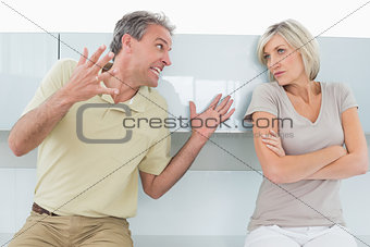 Woman with arms crossed as man argue in kitchen