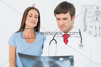Male doctor explaining lungs x-ray to female patient