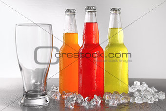 Three bottles with drinks with glass and ice
