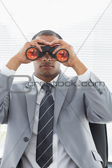 Serious businessman looking through binoculars