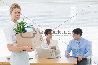 Businesswoman carrying her belongings with colleagues in background