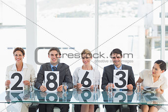 Group of panel judges holding score signs