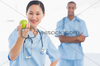 Female surgeon holding an apple with colleague in hospital