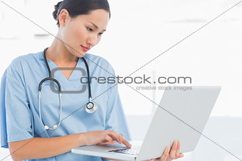 Concentrated surgeon using a laptop in hospital
