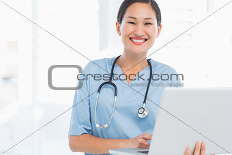 Smiling female surgeon using a laptop