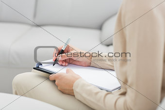 Mid section of a financial adviser writing notes