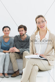 Female financial adviser with young couple in background