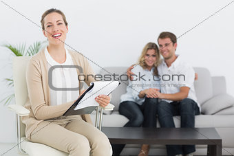 Financial adviser writing notes with couple in background