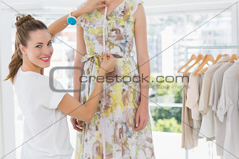 Portrait of a female fashion designer measuring model