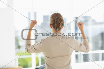 Rear of a businesswoman clenching fists in office