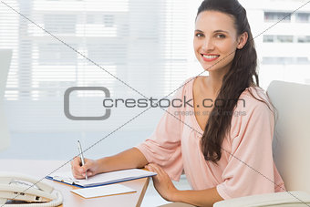 Businesswoman writing on clipboard at a bright office