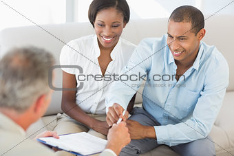 Young smiling couple listening to salesman on the couch