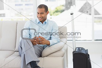Happy businessman sitting on sofa waiting to depart on business trip