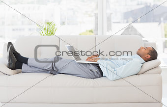 Businessman asleep on the sofa with laptop