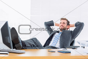 Relaxed businessman sitting with legs on desk