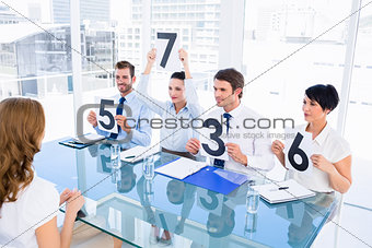 Group of panel judges holding score signs in front of woman