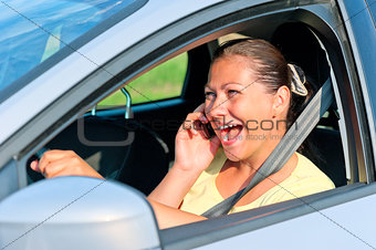 beautiful girl behind the wheel with phone laughing