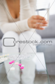 Closeup on pills and young woman in background
