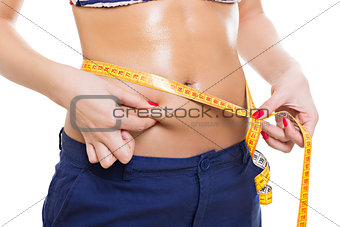 Fit woman pinching fat and measuring belly