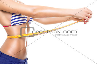 Fit young woman in bikini measuring her waist