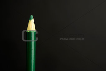 Green pencil crayon on a black background