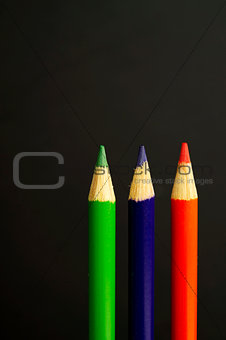 green, purple and orange coloured pencil crayons on a black back