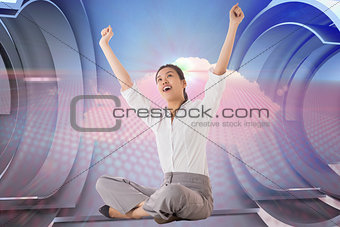 Composite image of businesswoman sitting cross legged cheering