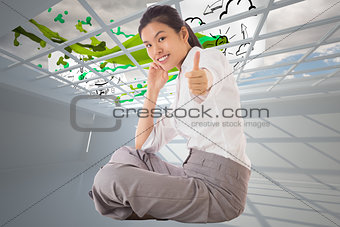 Composite image of businesswoman sitting cross legged showing thumb up