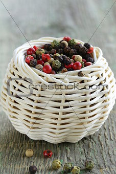 colorful peppercorn in wicker bowl on wooden table