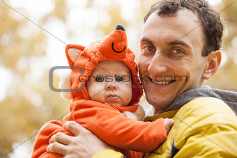 Young Caucasian man and his little son in fox costume in autumn park