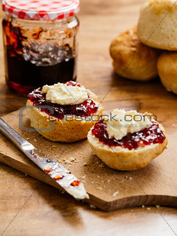 Two scones prepared with clotted cream and jam