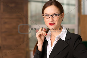 Business Woman Pauses Pen in Hand in Office Eyeglasses