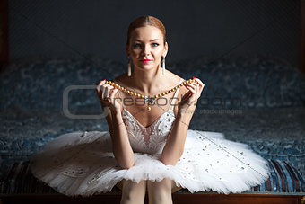 Ballerina holding pearl necklace and smiling