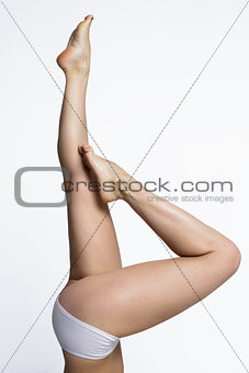 Waxing woman smooth legs pointing up on a white background