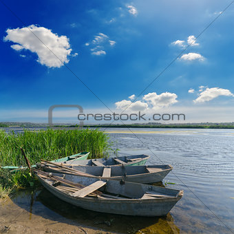 beautiful river and old boats near green grass under cloudy sky