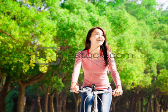 Pretty asian young woman riding bike in the park