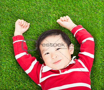 little smiling boy resting and hand up  in meadow