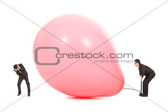 Businessmen scared balloon is inflated to burst