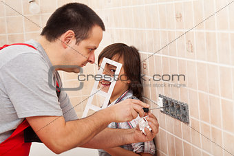 Boy assisting his father in electrician work