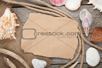 Old paper with rope and seashells on wooden textured background